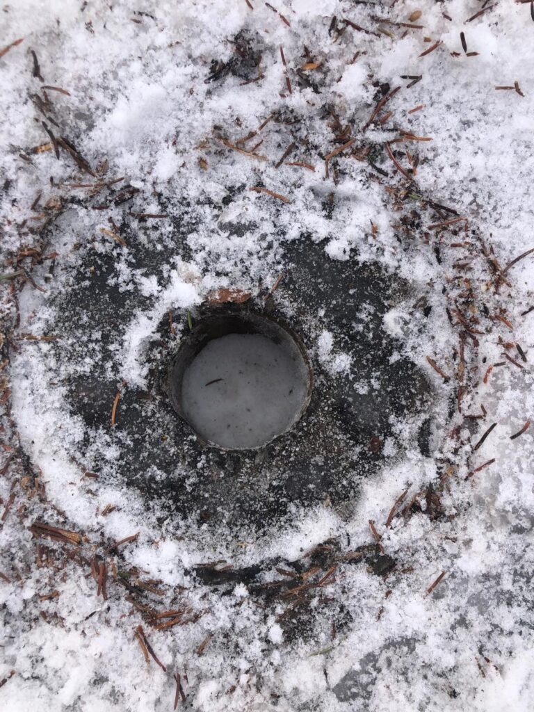 En hiver : un drain dégagé au milieu de la neige et de la glace.