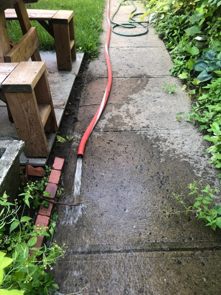 Au sol, le boyau évacue l'eau du toit vers le trottoir, loin du bâtiment.