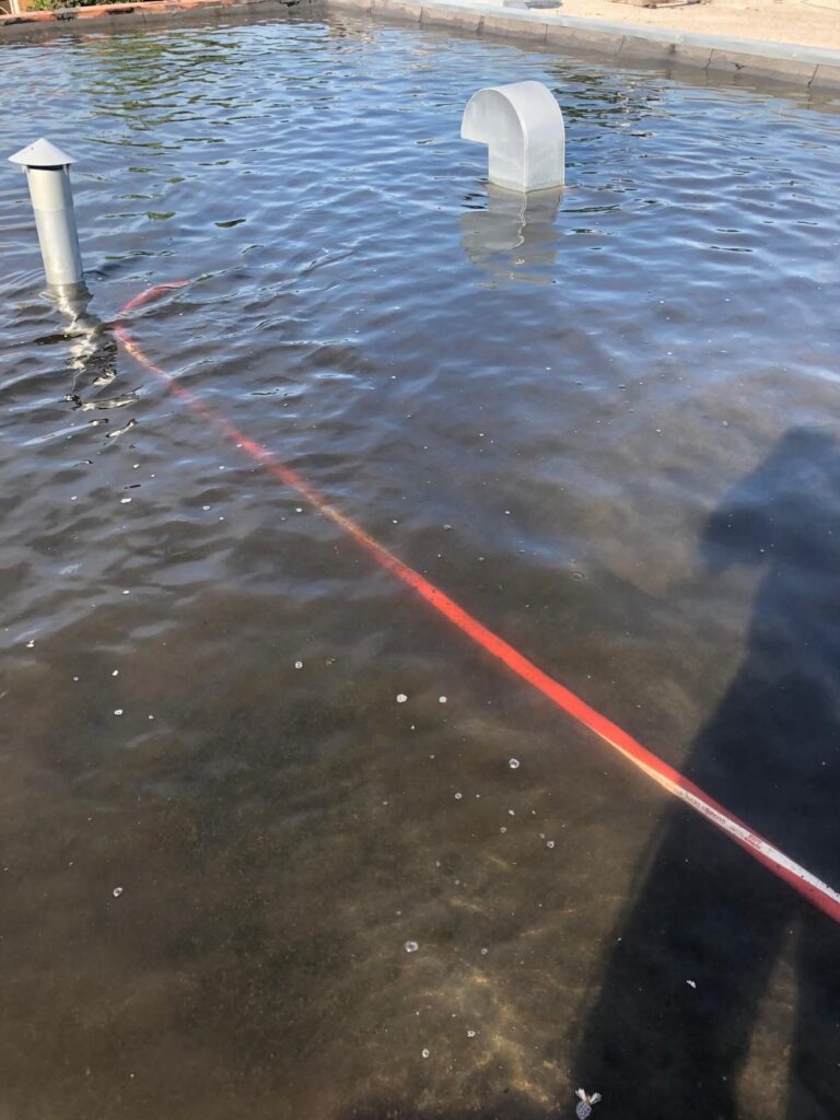 Le boyau de pompage traverse l'eau jusqu'au point le plus bas du toit.